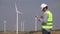 Engineer near windmills turbines writing down the technical parameters