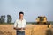 Engineer with notebook and combine harvester in field