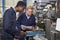 Engineer Showing Apprentice How to Use Drill In Factory