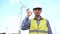 Engineer showing ok with safety helmet in front of wind turbines ecological energy industry power windmill