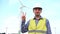 Engineer showing victory with safety helmet in front of wind turbines ecological energy industry power windmill