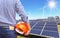 Engineer stand holding safety yellow helmet with solar cells and wind turbines generating electricity in hybrid power plant system