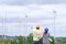 An engineer stands holding a blueprint and looks a wind turbine project to generate electricity and check wind direction