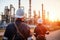 Engineer survey of oil refiner and control worker from portable radio on storage tank in sunset background