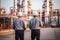 Engineer survey of oil refiner and control worker from portable radio on storage tank in sunset background