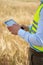 an engineer with a tablet in his hands stands in the middle of a green field, an agronomist in a field with wheat checks the