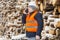 Engineer talking on the smartphone near to piles of logs in winter