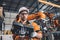 Engineer team service robot welding working in automation factory. Male worker operate robotic arm software hand controller in
