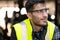 Engineer or technician wearing safety glasses and vest sitting on the floor and relax in the metalworking factory. He is looking