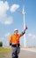 Engineer or technician worker stand in front of windmill or wind turbine and point to left side in concept of confidence and