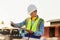 Engineer in waistcoats and hardhats with clipboard checklist inspecting construction site, Smiling mechanical worker checking of