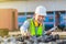 Engineer in waistcoats and hardhats with documents inspecting construction site, Smiling mechanical worker checking of the battery