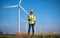 Engineer wearing uniform ,helmet inspection and survey work in wind turbine farms rotation to generate electricity energy. Green e