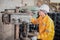 Engineer wearing yellow work clothes white hardhat and wear glove using drilling machine, Industry and production concept