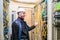 An engineer in a white helmet is happy with his work in the server room. Cheerful technician waves his hand in the data center.