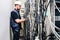 An engineer in a white helmet unravels many wires in a data center. A technician working connects a lot of cables in a server rack