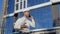 An engineer in a white shirt and helmet works on the construction of a modern glass building. Architect engineer reads