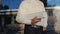 An engineer in a white shirt and helmet works on the construction of a modern glass building and holds a drawing of the