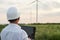 Engineer in a wind turbine. A man in a helmet with the tablet supervises the operation of the electric windmills. Ecology and