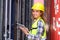 Engineer women wear yellow helmets and reflection shirts working on tablet computers to check inventory details of containers box