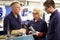 Engineer Working With Apprentices On Factory Floor