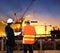 engineering man working in building construction site with worker foreman against beautiful dusky sky