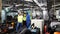 Engineers and employees walk inside the factory at break. Engineers and industrial workers are working on large machines.