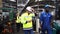 Engineers and employees walk inside the factory at break. Engineers and industrial workers are working on large machines.