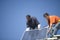 Engineers Fixing Solar Panel Against Blue Sky