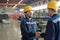 Engineers in protective hardhats and workwear shaking hands of one another in workshop environment