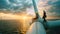 Engineers rest on top of wind turbine in sea at sunset, workers perform maintenance of windmill in ocean on sky and sun background