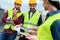 engineers in safety vests and hardhats working with digital tablet