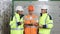 Engineers in uniform and helmets with digital tablet do pre-commissioning works inspecting electrical station in sunny