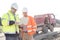 Engineers using laptop at construction site against clear sky on sunny day