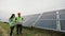 Engineers workers holding solar plan in hands and standing near solar panel station. Woman and man in special uniform