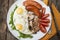 English breakfast. Eggs, sausages, mushrooms, tomatoes, toast bread. Eating tasy food over rustic wooden table.