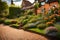 English cottage garden in the backyard, green grass and colorful flowering plants, brown paving and an orange brick wall