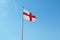 The English flag flies against a blue sky