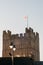 English Heritage flag atop the keep of Richmond Castle, North Yorkshire with steam rising from rooftops in the foreground and