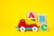 English letters ABC on wooden blocks in a toy plastic truck on a yellow background