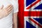 English person with hand on heart on the background of UK flag. Patriotism, country, national, pride concept