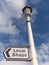 English Street Sign for Local Shops against blue sky with clouds background.