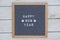 English text happy new year and two stars on a felt Board in a wooden frame. white letters on a gray background. letterboard on