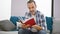 Engrossed middle age man with grey hair, comfortably sitting on his living room sofa, absorbed in reading a book at home