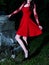 Enigmatic Gothic Beauty: Mysterious Woman in Crimson Red Dress Poses Among Ancient Stones