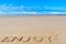Enjoy inscription on wet beach sand under the sun drawing and se