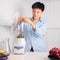 Enjoying Asian man preparing to Make a Smoothie with Swiss Chard, banana, and red grape at a white kitchen home. people are taking