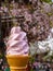 Enjoying delicious sweet pink sakura japanese ice cream soft serve cone under cherry blossom tree branches background