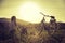 Enjoying the evening sun, sundown scenery: woman with bike is sitting in the green grass