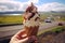 Enjoying local delight, hand holds ice cream against stunning Icelandic scenery